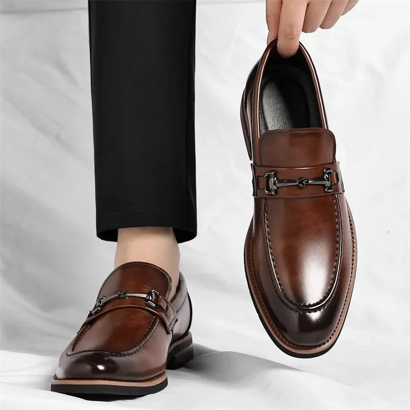 Brown leather loafers being worn with a white background