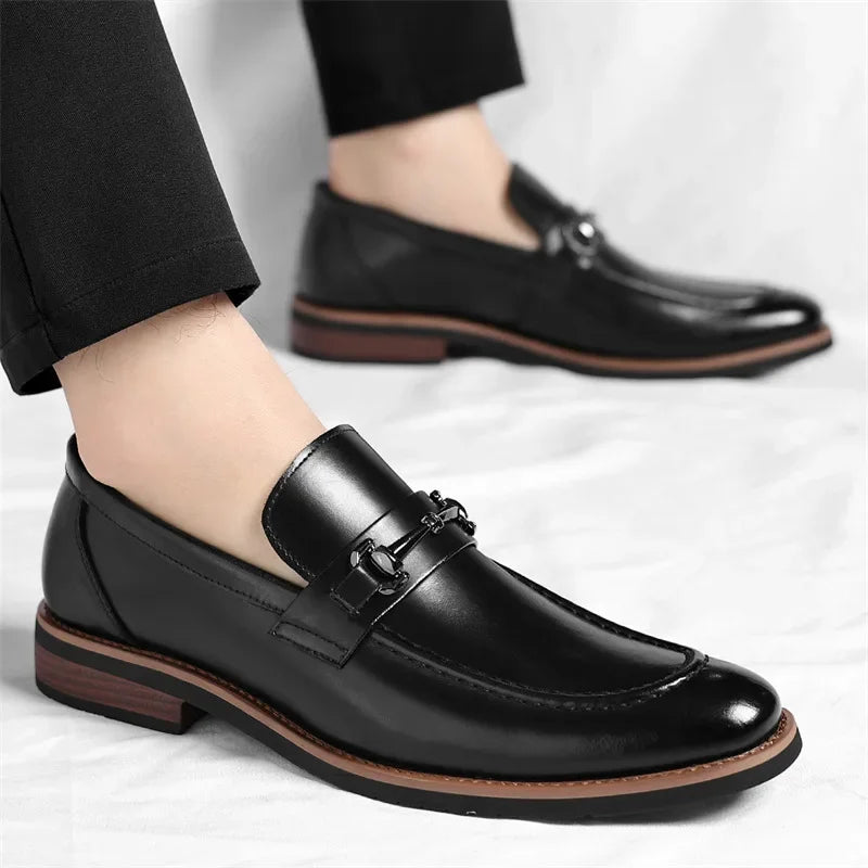 Black leather loafers worn with black pants on a light gray background